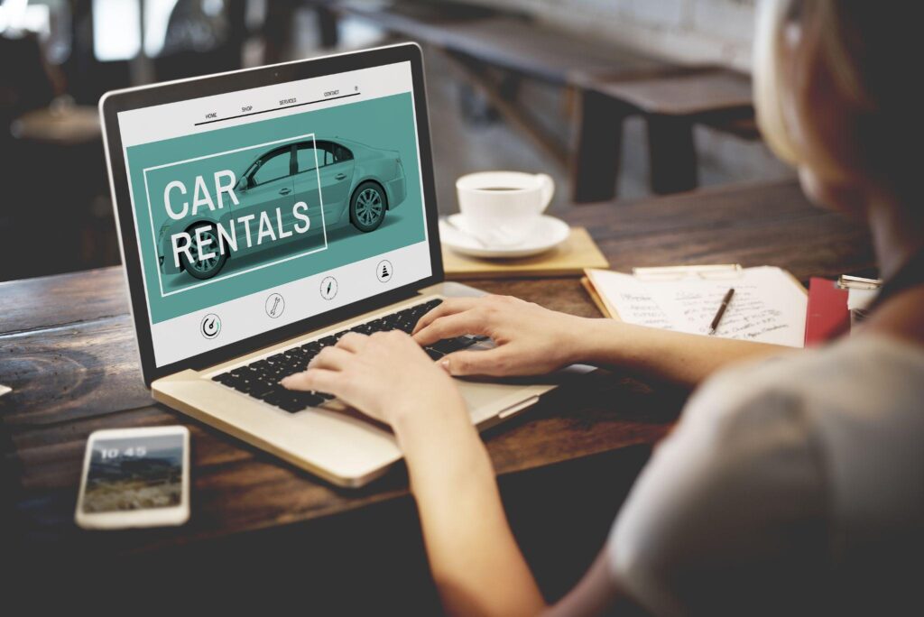 Close-up of a person using a laptop to book a car rental online, highlighting the ease of reserving with a small rental company