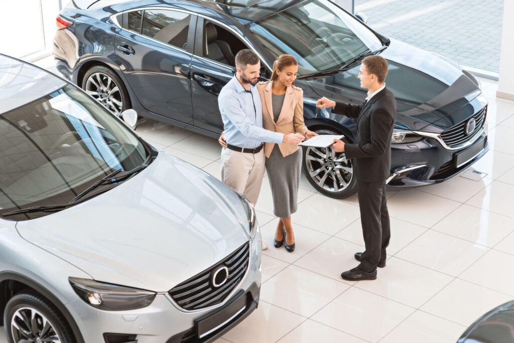 Couple reviewing a rental agreement with a staff member at a car rental agency, representing personalized customer service