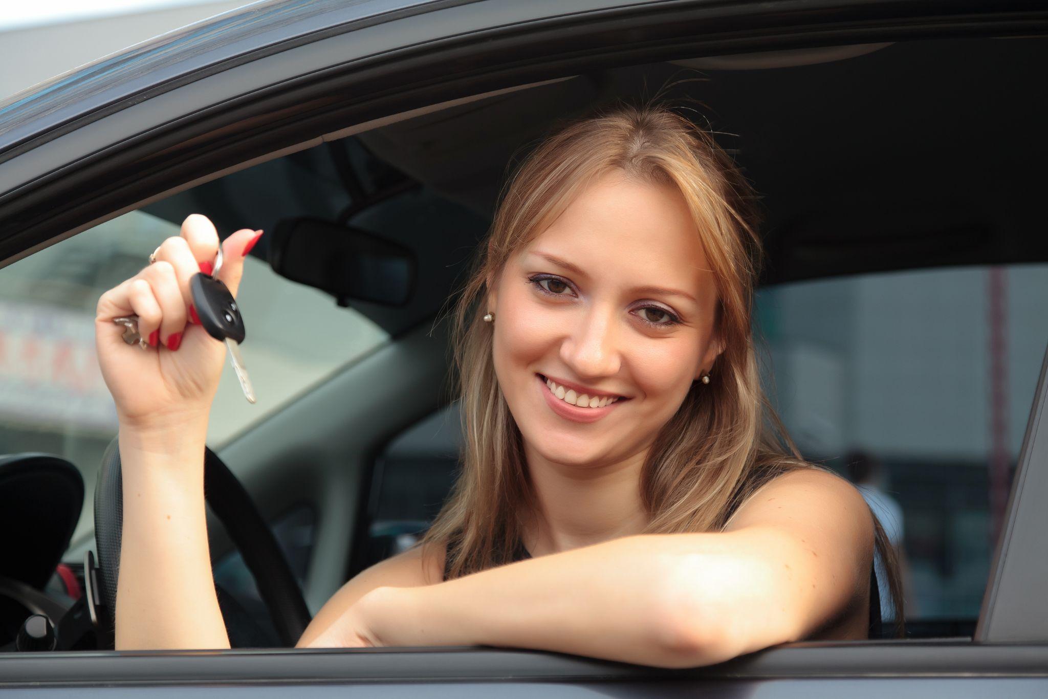 Smiling woman holding car keys from her rental car window, showing satisfaction with a local car rental experience