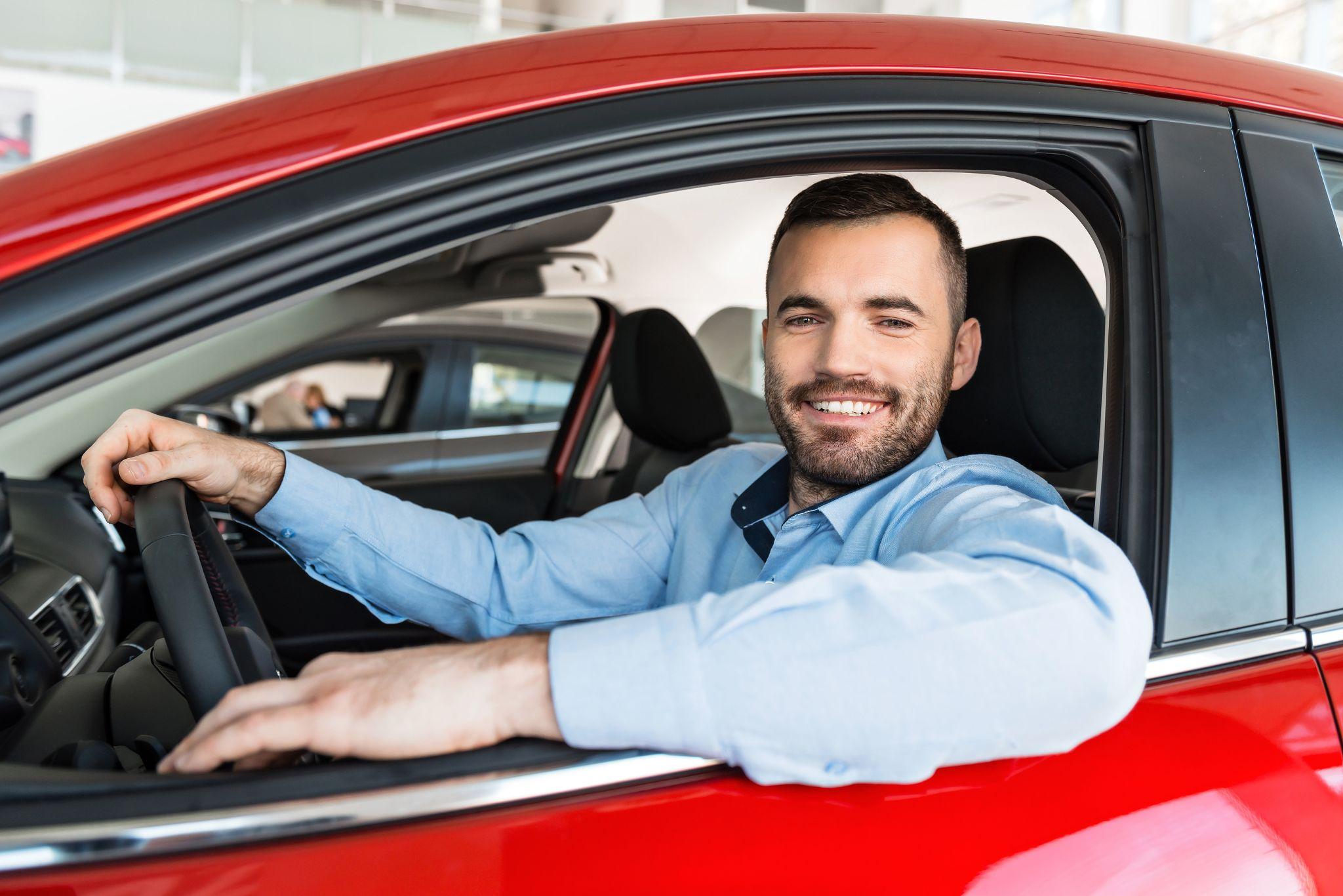 Smiling man sitting in his rental car, enjoying a smooth rental experience from a local provider